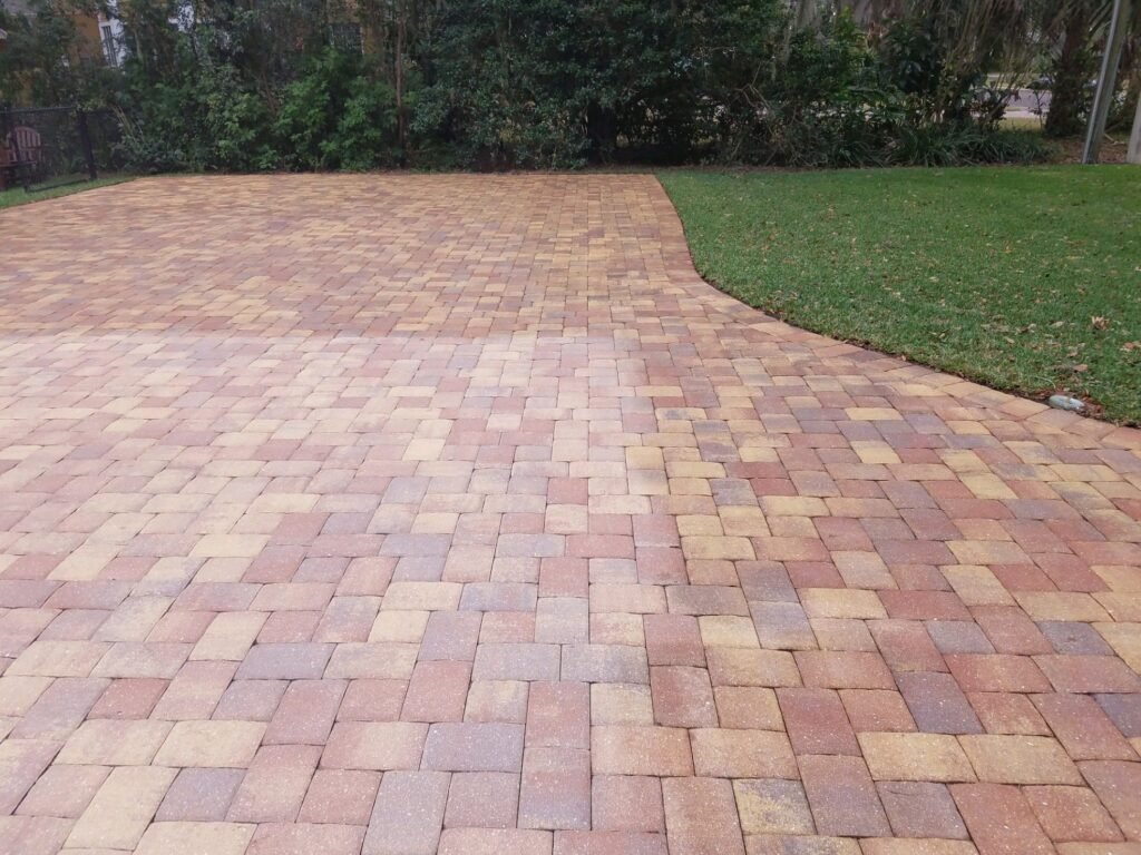 a brick walkway with grass and trees, paver cleaning and sealing in Lakeland, FL